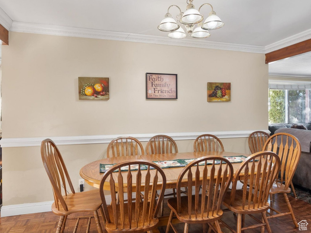 Dining room featuring a chandelier, ornamental molding, and parquet flooring