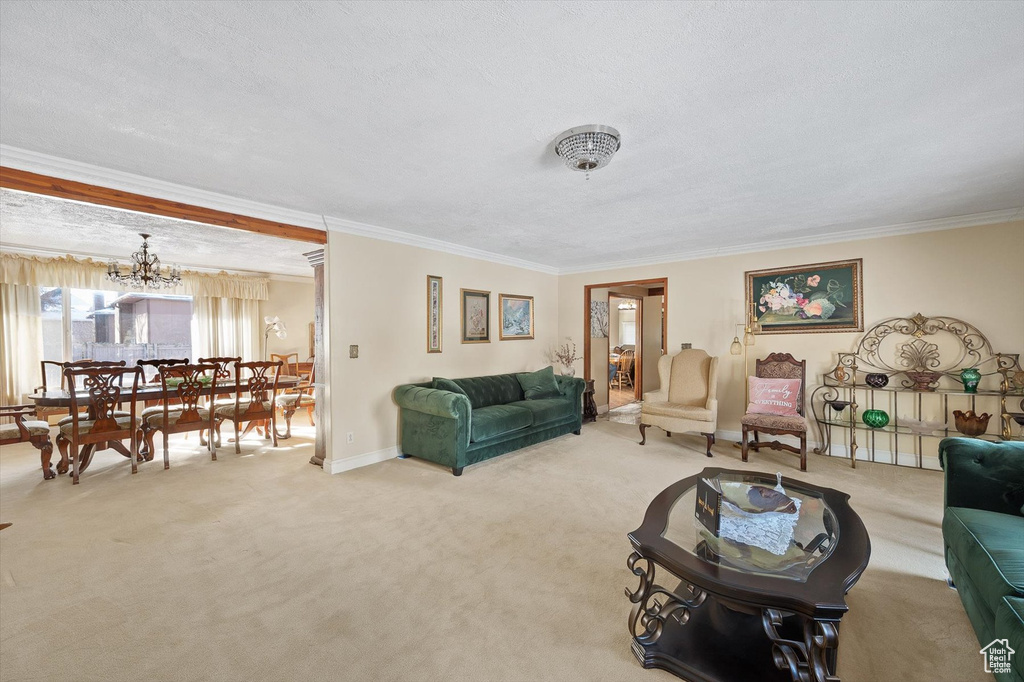 Living room featuring crown molding, a notable chandelier, a textured ceiling, and light carpet