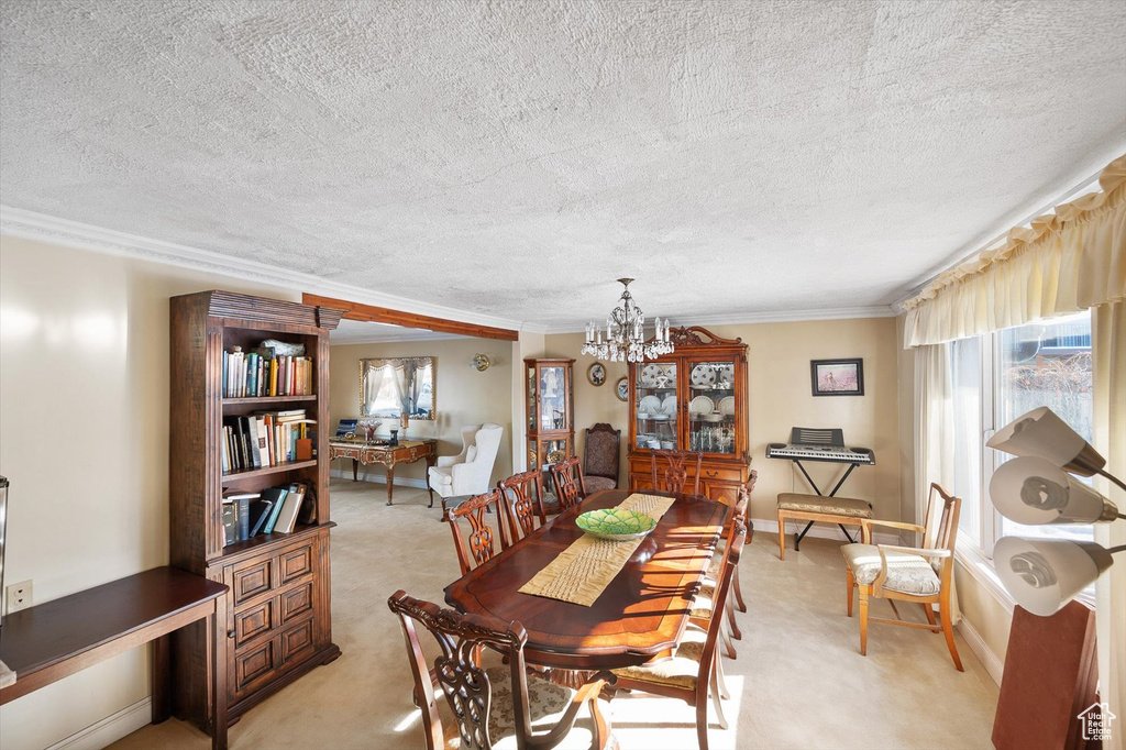 Dining room featuring a textured ceiling, light carpet, a notable chandelier, and ornamental molding