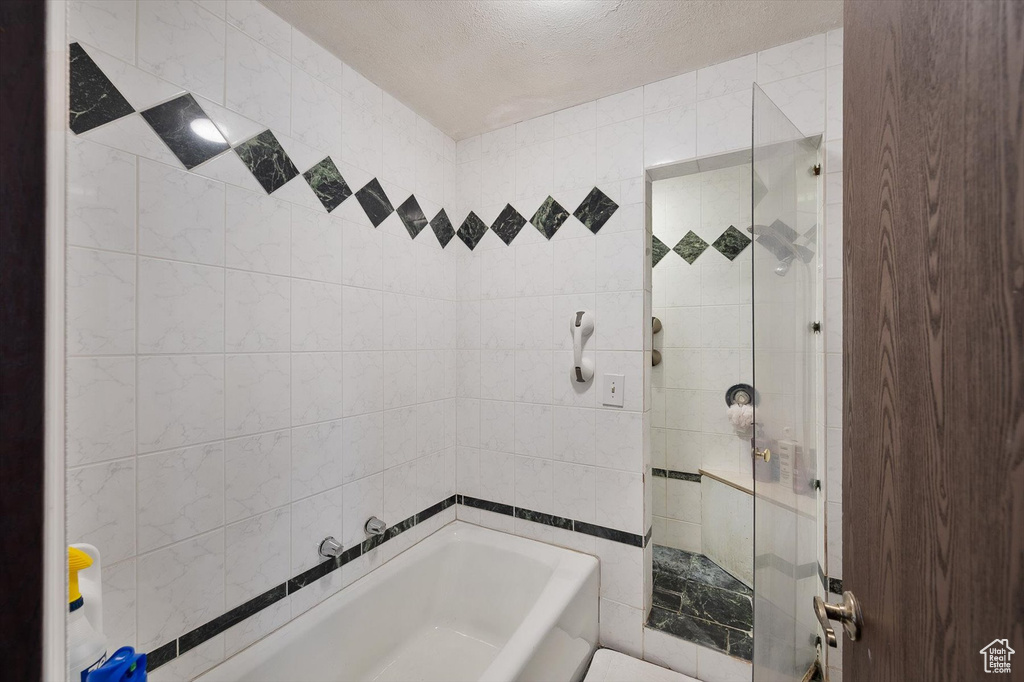 Bathroom featuring tiled shower / bath and tile walls