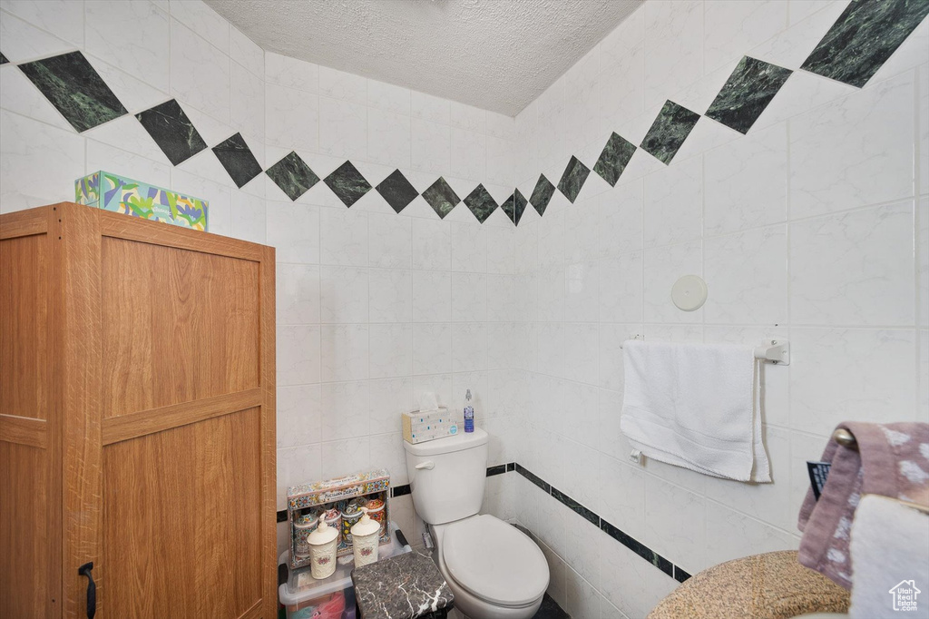 Bathroom with tile walls, toilet, and a textured ceiling