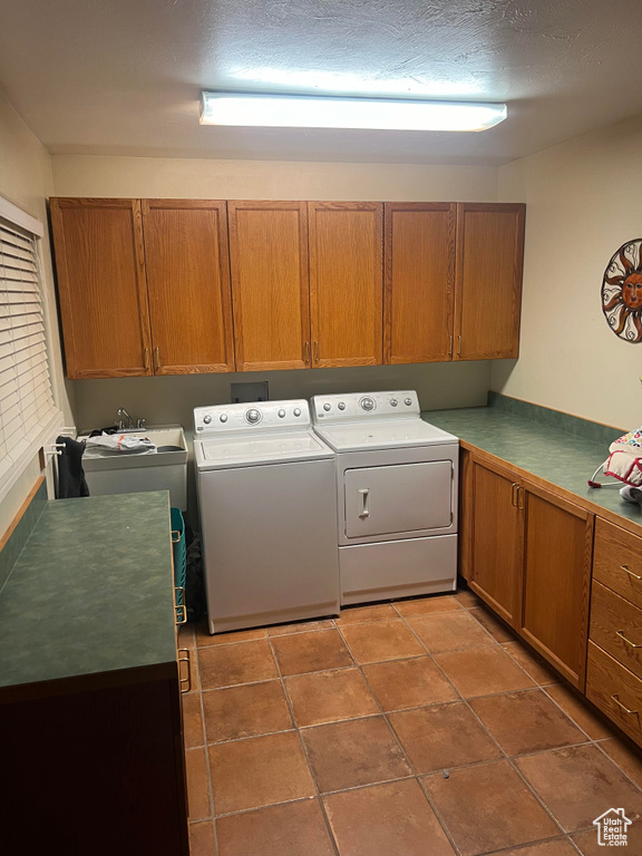 Laundry room featuring independent washer and dryer, tile floors, a textured ceiling, and cabinets