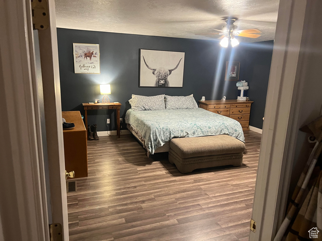 Bedroom featuring a textured ceiling, hardwood / wood-style flooring, and ceiling fan
