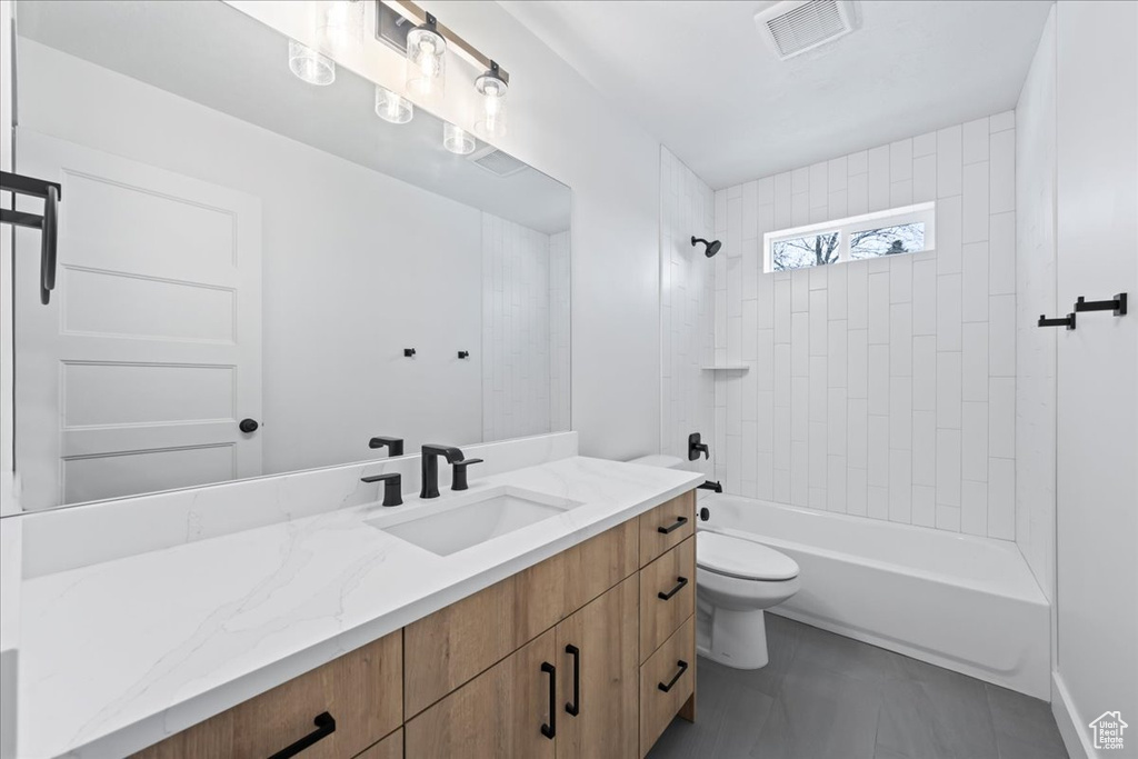 Full bathroom featuring tile floors, tiled shower / bath, large vanity, and toilet