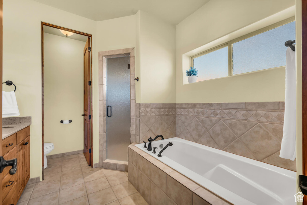 Full bathroom featuring independent shower and bath, toilet, tile floors, and vanity
