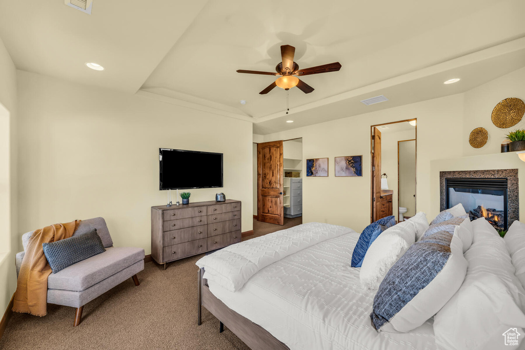 Bedroom featuring light colored carpet, a raised ceiling, ceiling fan, and ensuite bathroom