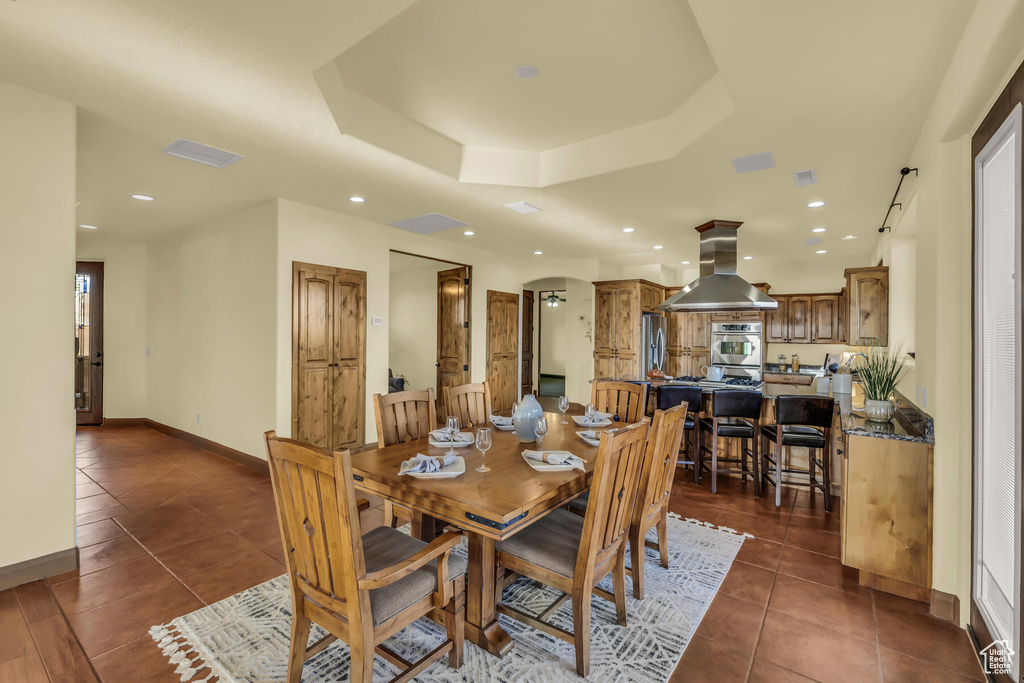 Dining area featuring dark tile floors and a tray ceiling