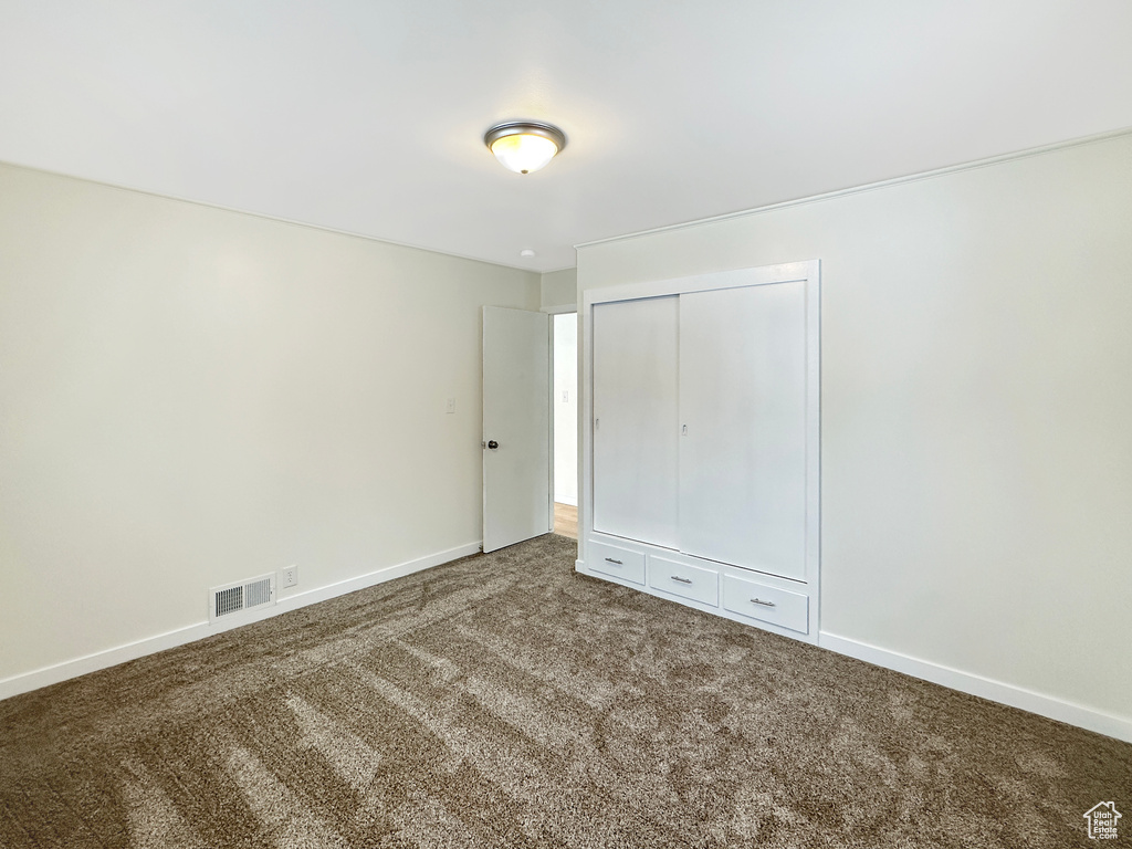 Interior space featuring a closet and dark colored carpet