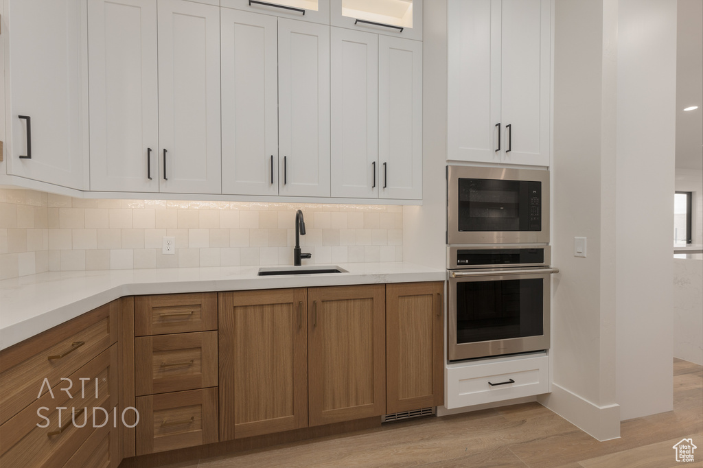 Kitchen featuring black microwave, light hardwood / wood-style flooring, white cabinetry, and stainless steel oven