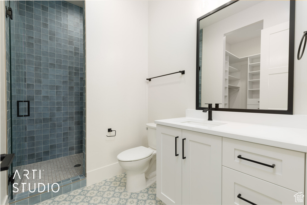 Bathroom featuring vanity, toilet, a tile shower, and tile flooring