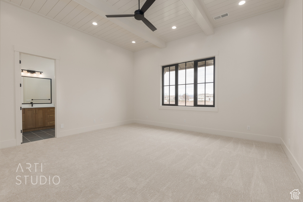 Empty room featuring light colored carpet, beam ceiling, and ceiling fan