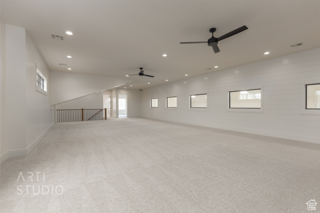 Unfurnished living room with a healthy amount of sunlight, light carpet, and ceiling fan