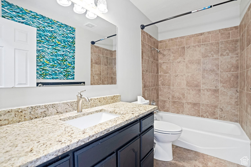 Full bathroom with tiled shower / bath, toilet, tile flooring, and oversized vanity