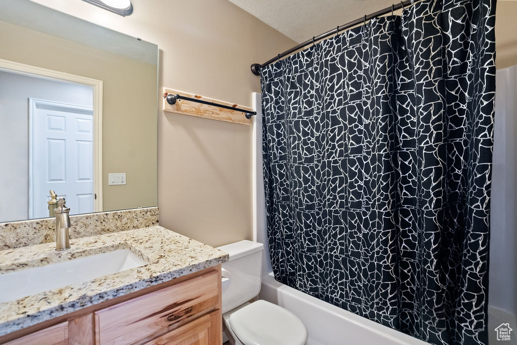 Full bathroom with toilet, vanity with extensive cabinet space, and shower / bath combo