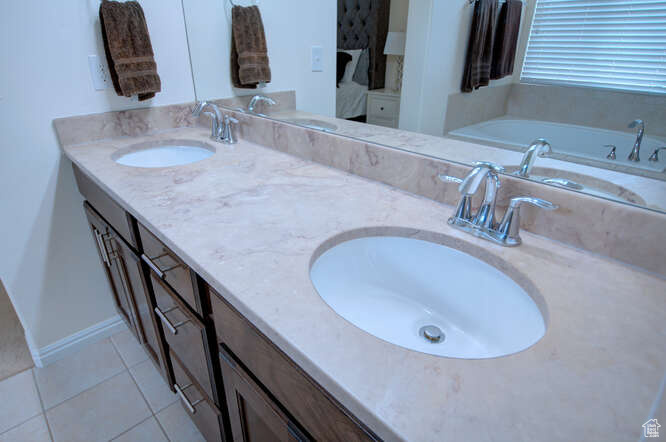 Bathroom featuring double vanity, a bathing tub, and tile flooring