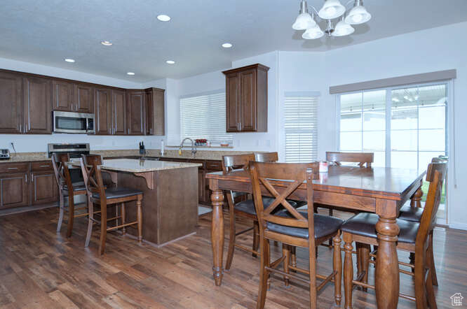 Kitchen with a kitchen island, pendant lighting, a notable chandelier, and dark hardwood / wood-style flooring