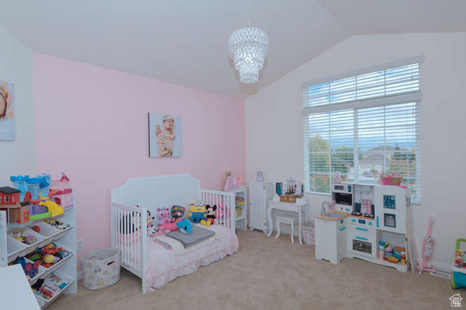 Bedroom with vaulted ceiling, light colored carpet, an inviting chandelier, and a nursery area