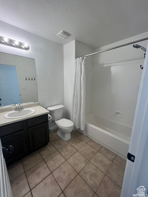 Full bathroom featuring toilet, vanity with extensive cabinet space, tile flooring, and shower / tub combo