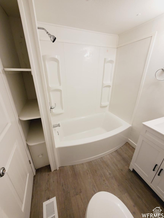 Full bathroom with hardwood / wood-style floors, toilet, shower / bath combination, and vanity