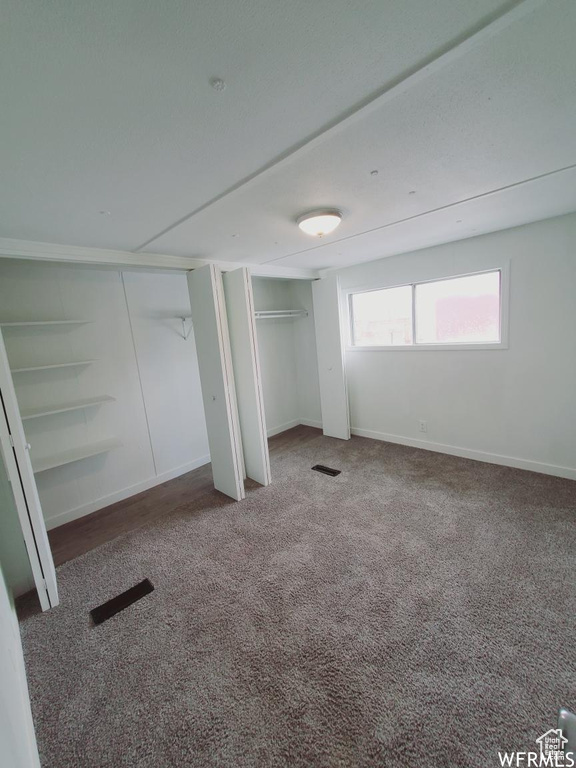 Unfurnished bedroom with multiple closets and dark carpet