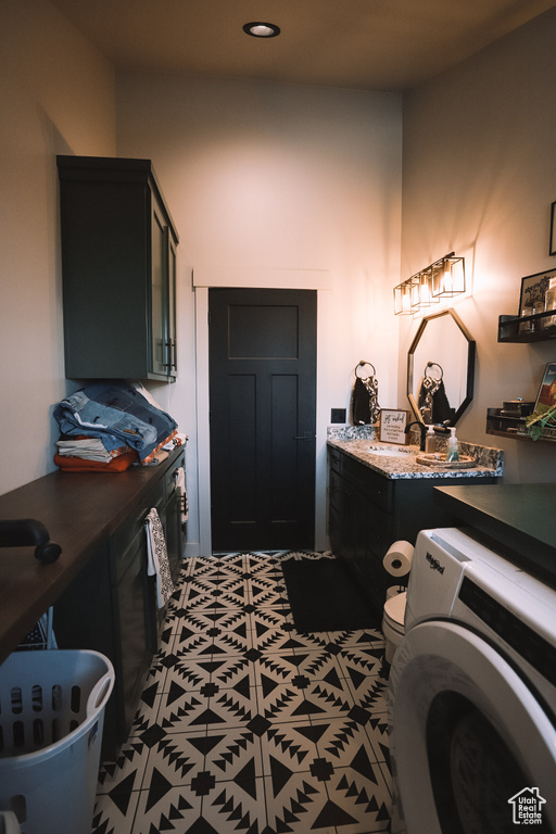 Interior space with a bath to relax in, toilet, vanity, washer / dryer, and tile flooring