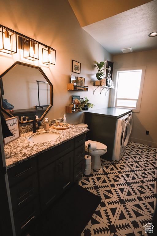 Bathroom featuring oversized vanity, toilet, washer / clothes dryer, tile flooring, and a textured ceiling