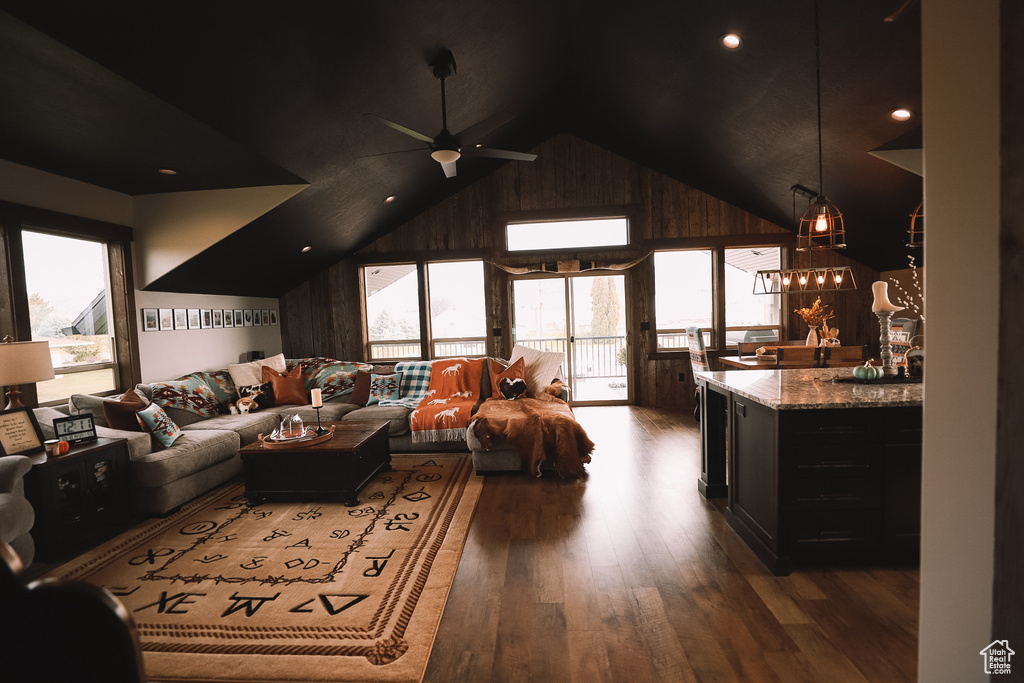 Living room with a healthy amount of sunlight, dark hardwood / wood-style floors, lofted ceiling, and ceiling fan