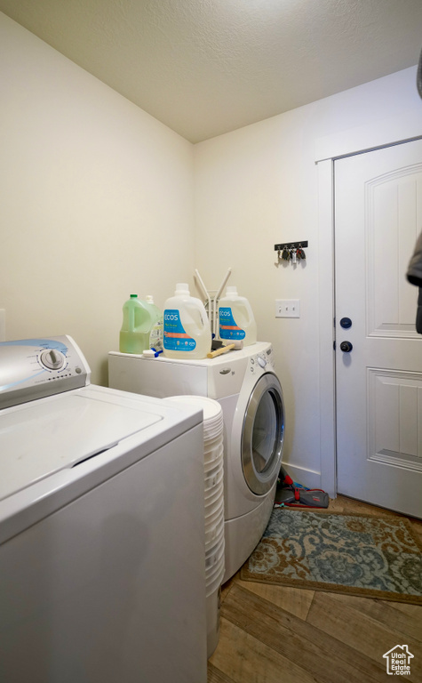 Clothes washing area with dark hardwood / wood-style flooring and washer and dryer