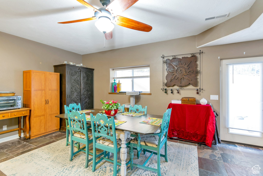 Dining area featuring dark tile flooring, a wealth of natural light, and ceiling fan