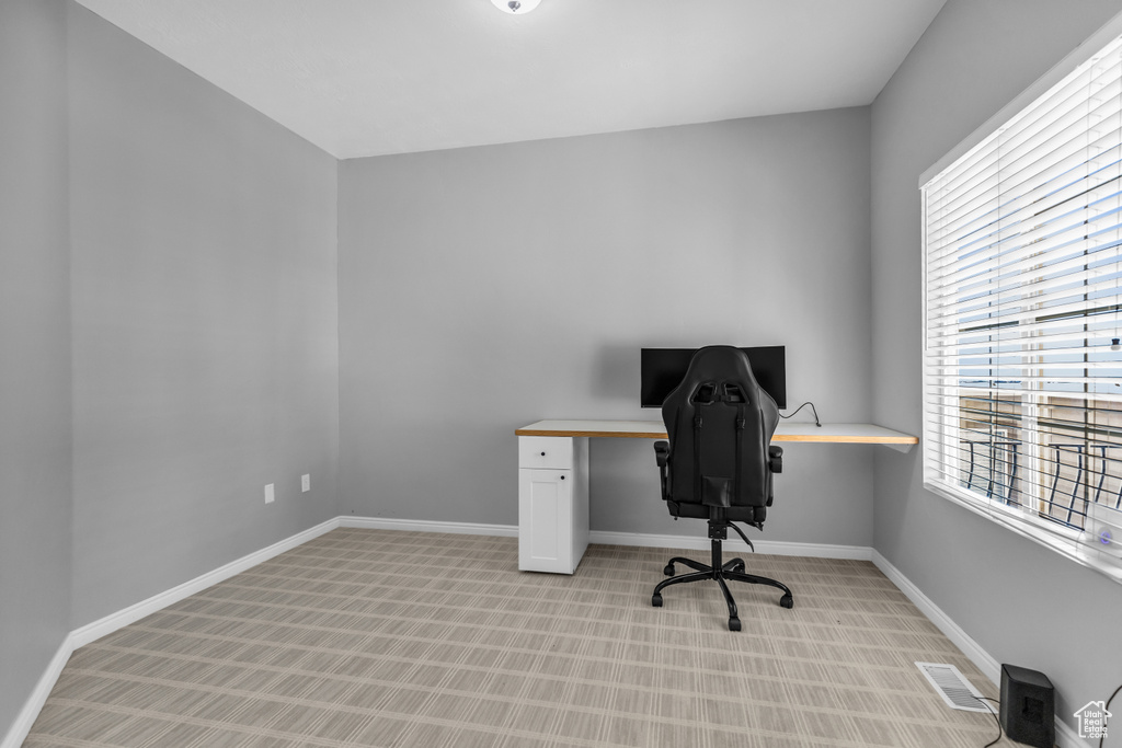Carpeted home office featuring built in desk