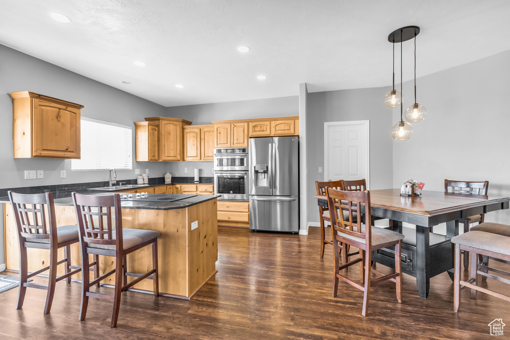 Kitchen featuring a kitchen island, dark wood-type flooring, decorative light fixtures, sink, and stainless steel appliances