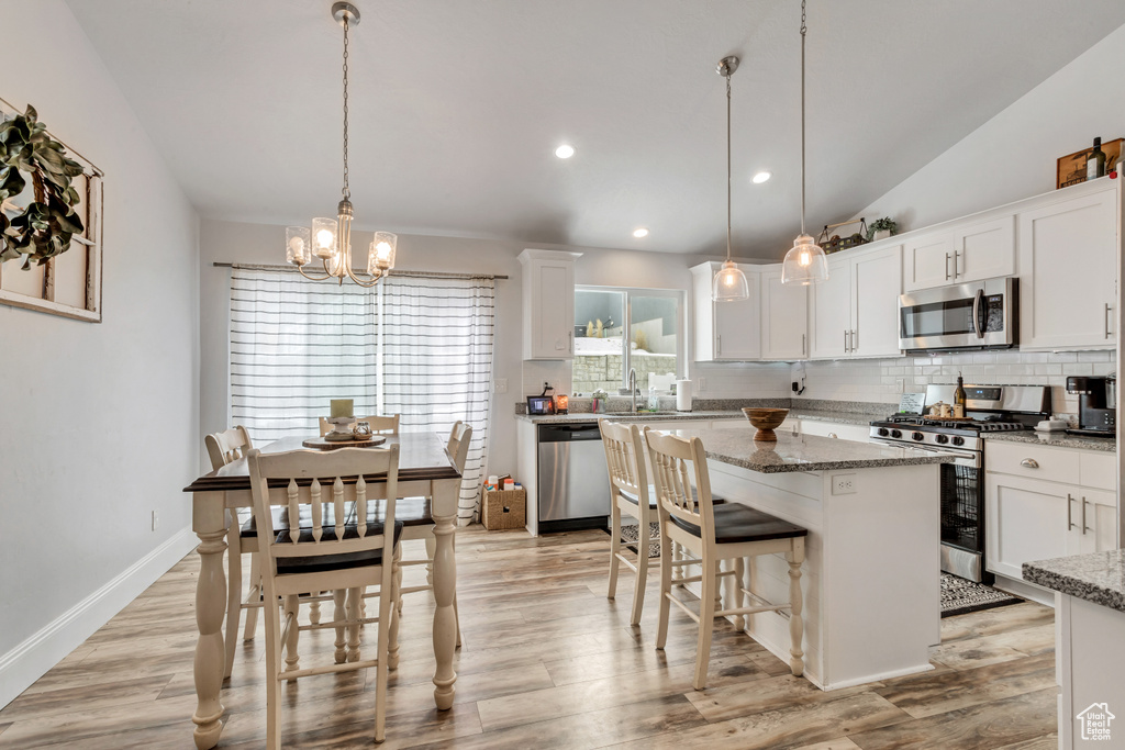 Kitchen featuring pendant lighting, light hardwood / wood-style floors, stainless steel appliances, and light stone counters