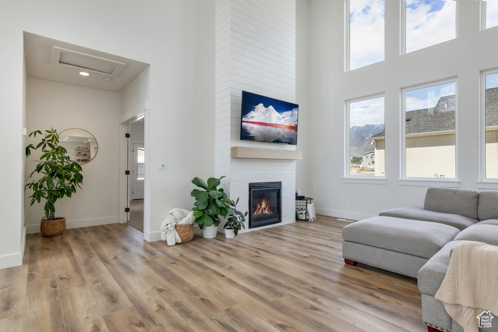 Living room featuring light hardwood / wood-style floors, a towering ceiling, and a large fireplace