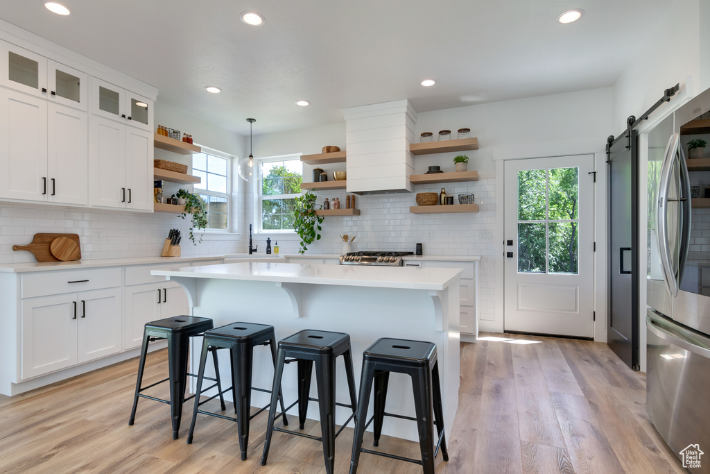 Kitchen featuring white cabinets, a barn door, backsplash, and light hardwood / wood-style floors