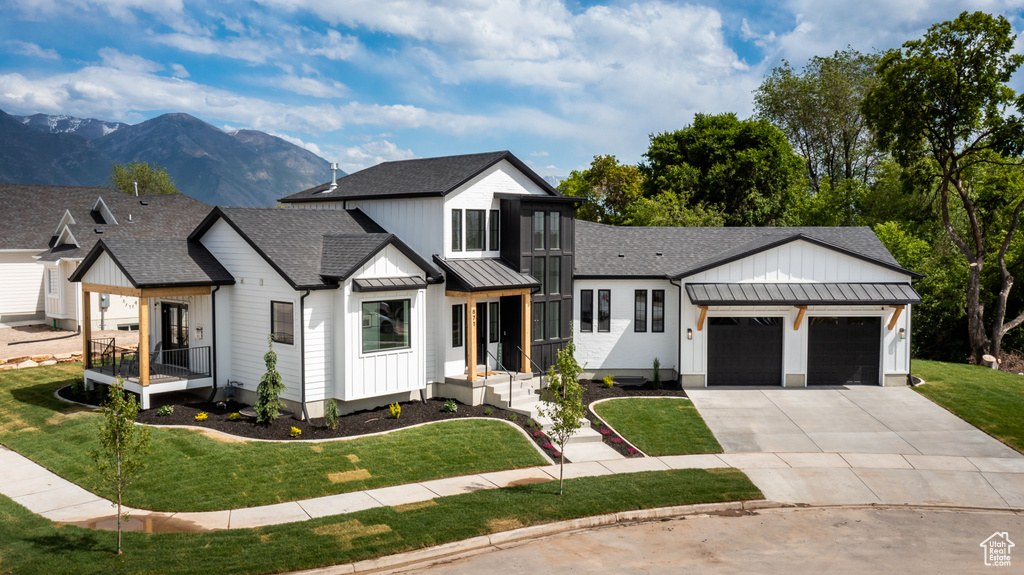 Modern farmhouse style home with a garage, a front lawn, and a mountain view
