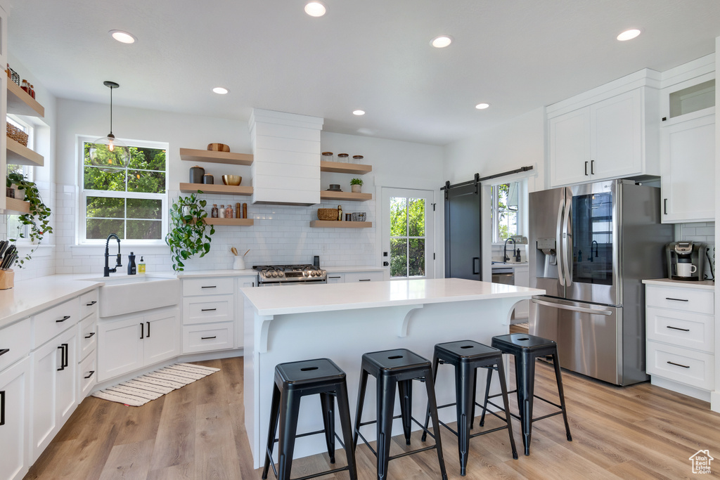 Kitchen featuring sink, tasteful backsplash, light hardwood / wood-style flooring, a barn door, and stainless steel appliances