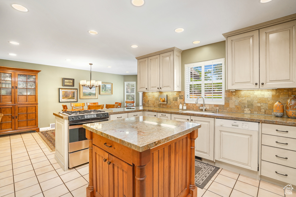 Kitchen featuring hanging light fixtures, sink, stainless steel gas range oven, and light tile floors