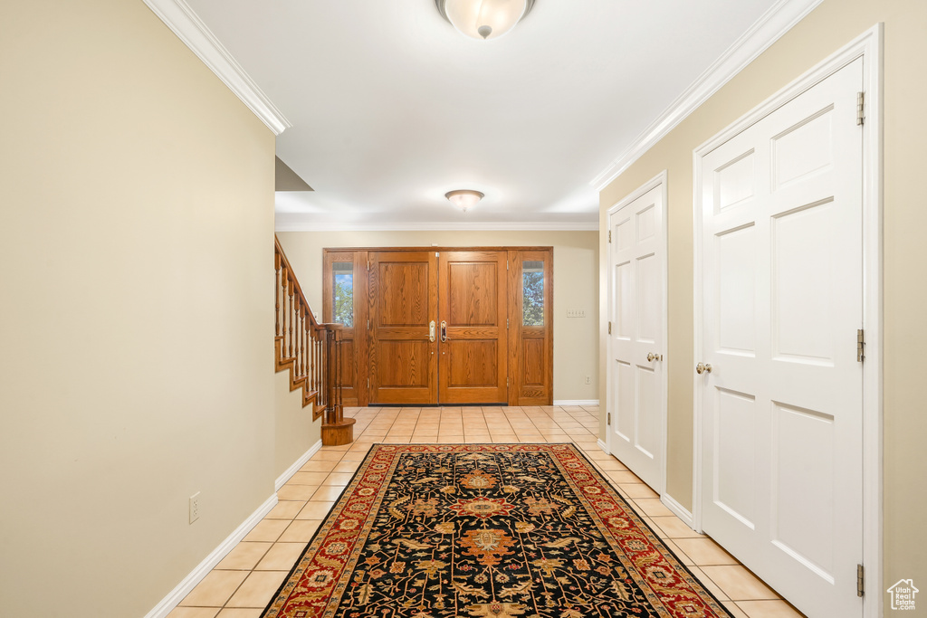 Doorway with ornamental molding and light tile flooring