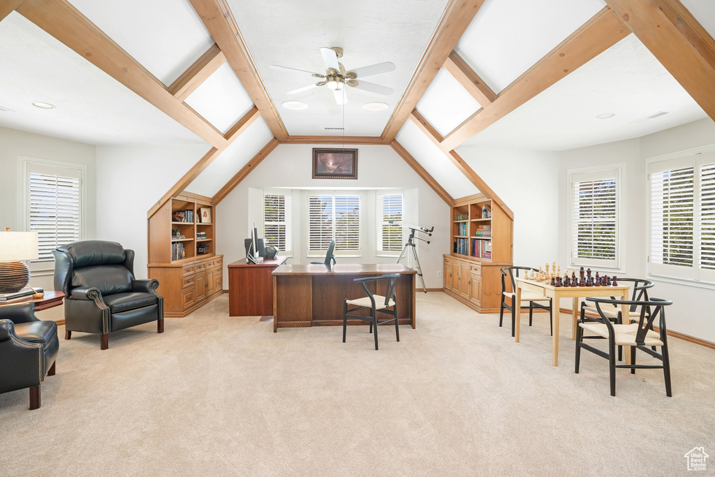 Carpeted home office with lofted ceiling with beams, ceiling fan, and a healthy amount of sunlight