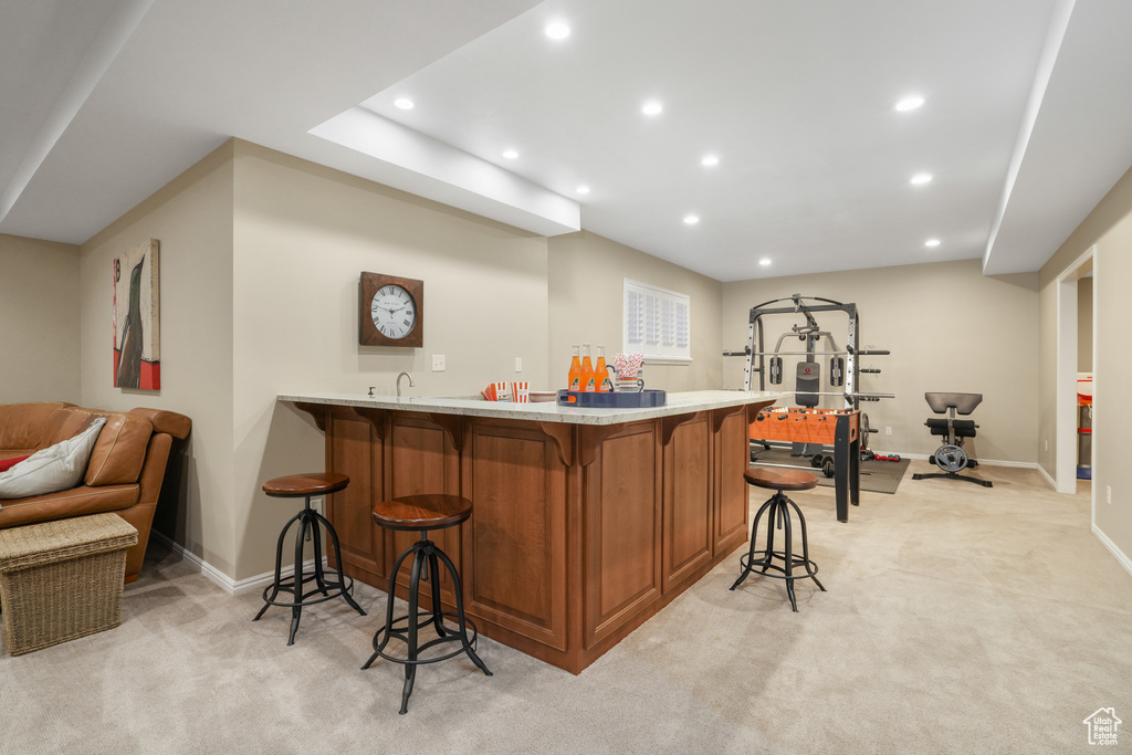 Bar featuring light stone countertops, sink, and light colored carpet
