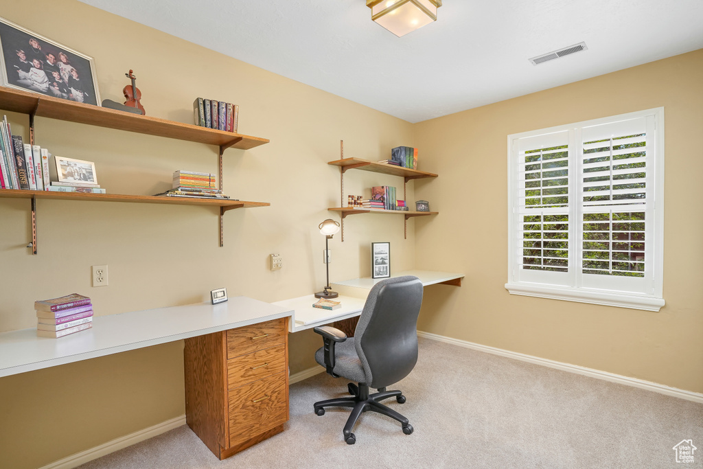 Office space with light colored carpet and built in desk