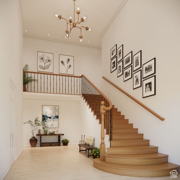 Stairs featuring a high ceiling, ornamental molding, and a chandelier