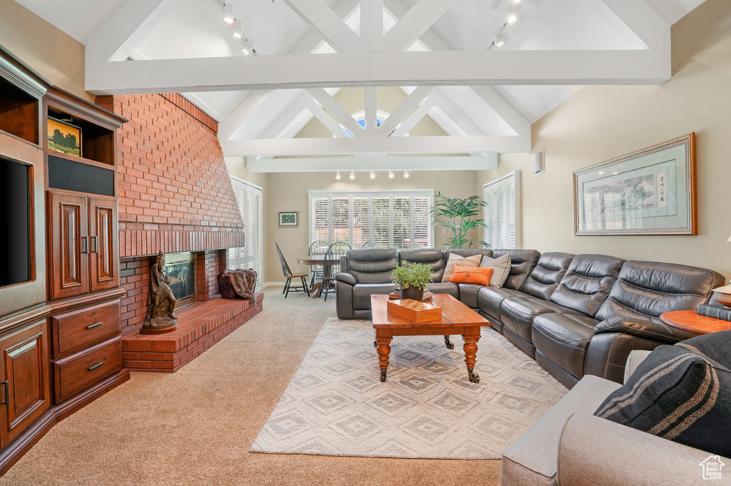 Living room featuring a brick fireplace, light colored carpet, brick wall, and beamed ceiling