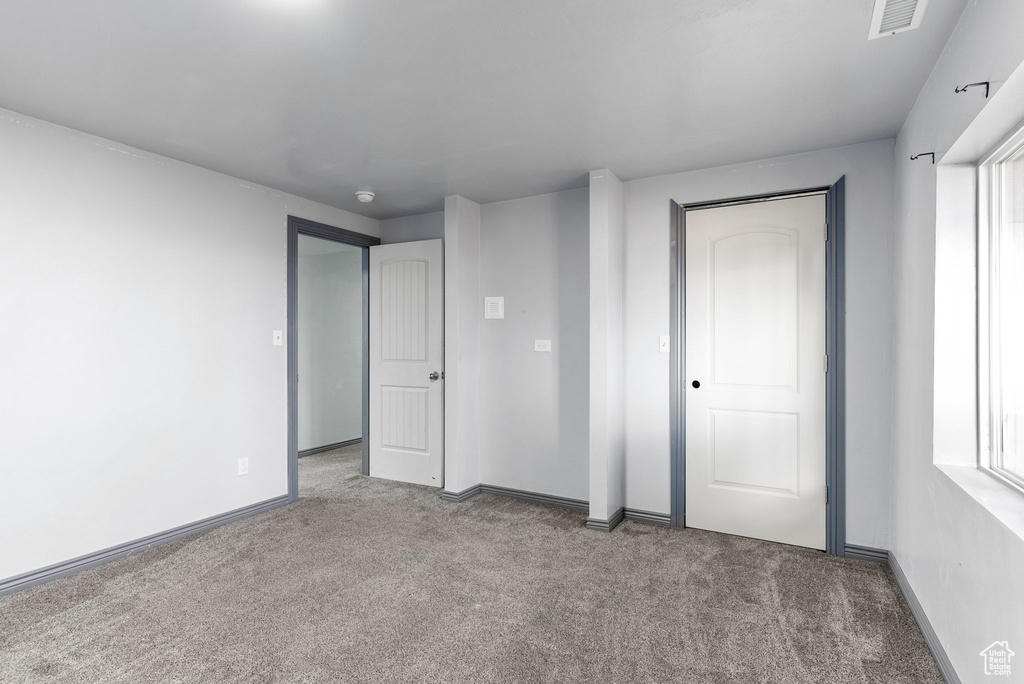 Unfurnished bedroom featuring a closet, multiple windows, and light colored carpet