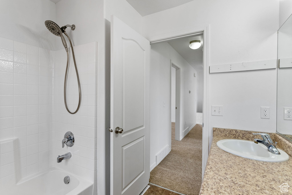 Bathroom with tile floors, tiled shower / bath, and vanity