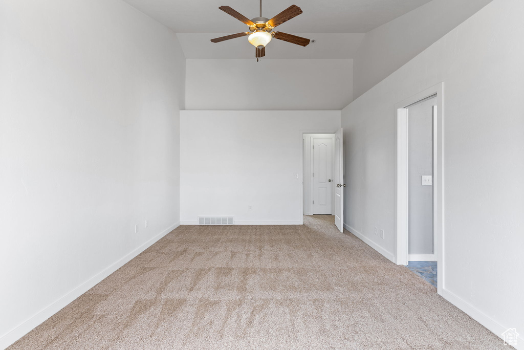 Carpeted spare room with vaulted ceiling and ceiling fan