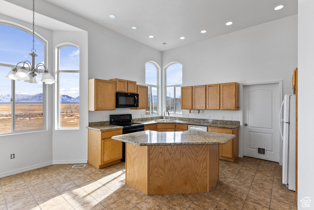 Kitchen with light tile flooring, a center island, black appliances, and a notable chandelier
