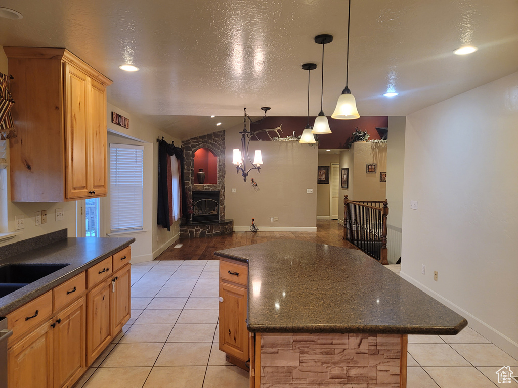Kitchen featuring light tile flooring, decorative light fixtures, a chandelier, a textured ceiling, and a center island