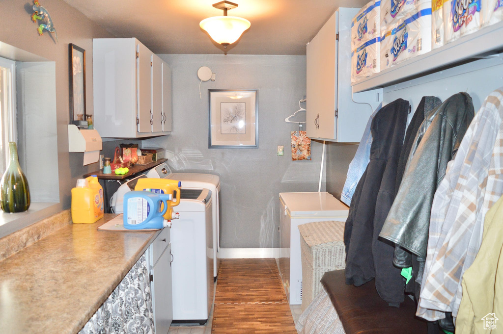 Laundry area with washing machine and clothes dryer, hardwood / wood-style floors, and cabinets