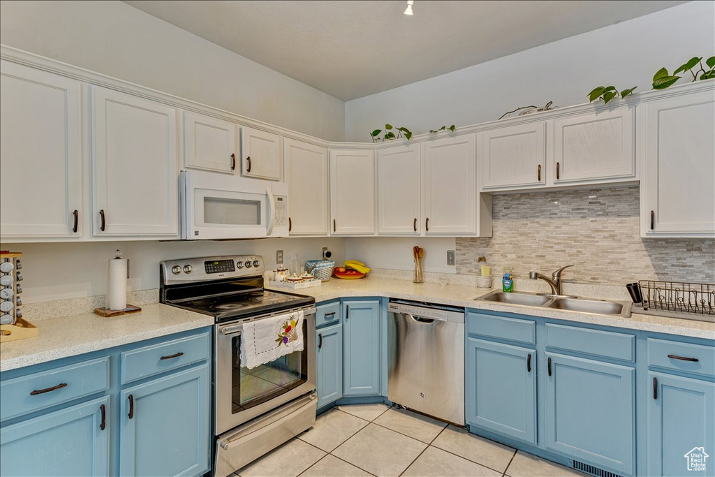 Kitchen featuring light tile floors, backsplash, white cabinets, sink, and stainless steel appliances